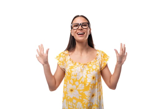 young pretty Caucasian woman in a yellow summer T-shirt carefully waves her hand in a friendly manner.