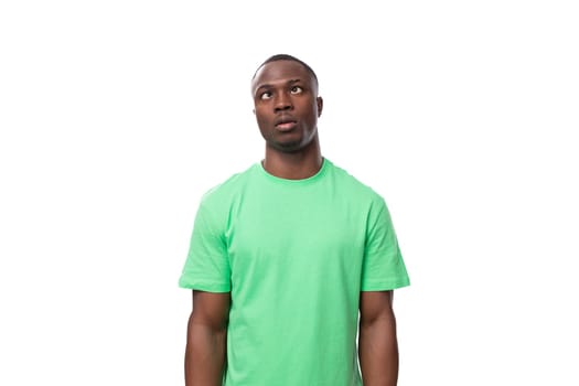 A 30-year-old smart African man dressed in a light green T-shirt is trying to remember a thought.