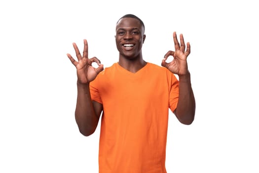 young american man in orange t-shirt feeling confident on white background with copy space.