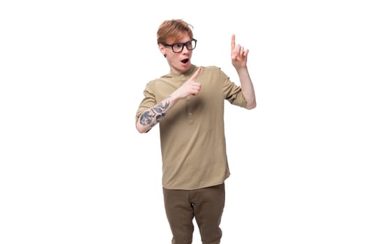 charming young European guy with red hair dressed in a trendy brown shirt wants to break the news pointing his finger.