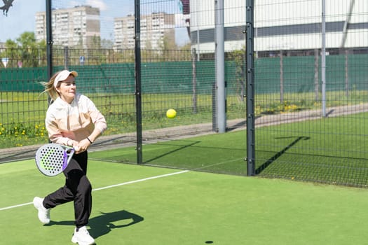 Young sporty woman performing basic strokes during paddle tennis group training. High quality photo