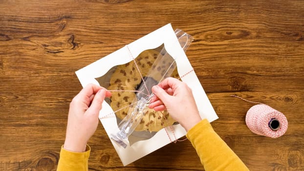 Flat lay. Carefully placing the gingerbread bundt cake, adorned with salted caramel frosting and gingerbread sprinkles, into a white paper bundt cake box with a clear window for gifting.