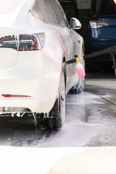 Efficiently cleaning an electric car in the comfort of a suburban driveway, combining eco-consciousness with practicality.