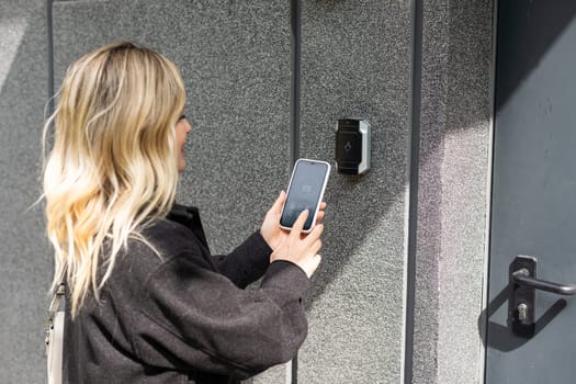 female entering secret key code for getting access and passing building using application on mobile phone, woman pressing buttons on control panel for disarming smart home system. High quality photo