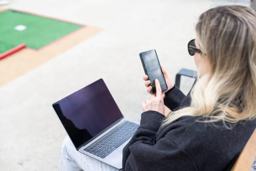 woman on golf course with smartphone with sports betting app. High quality photo