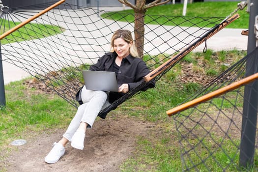 girl with a laptop on a bench in the park on a background of greenery. High quality photo
