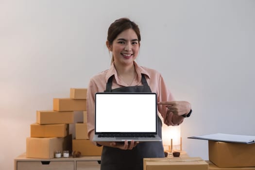 Portrait of Starting small Asian young businesses owners showing laptop with blank screen at home..