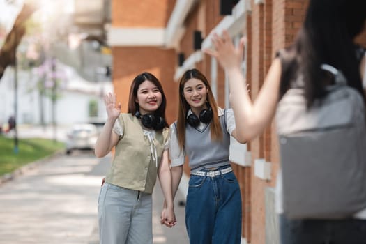 Group of Asian and happy students waving to his female friends Greeting his friends while walking in the park..