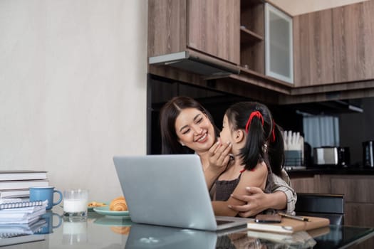 Working mom work from home office. Happy mother and daughter look to each other. businesswoman and cute child using laptop work freelancer workplace in living room.