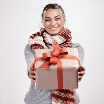 Christmas, woman and gift with smile in portrait for festive, winter and holiday on studio backdrop. Female person, cheerful and happy in celebration with present for season with decor for home.