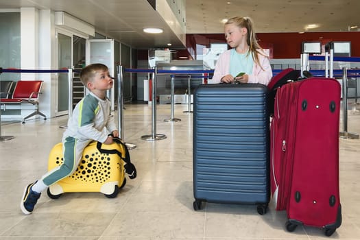 Children in the waiting room on suitcases flying to Paris at summer