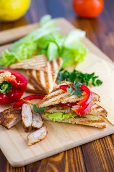 fried toast with chicken, salad, greens on a wooden table .