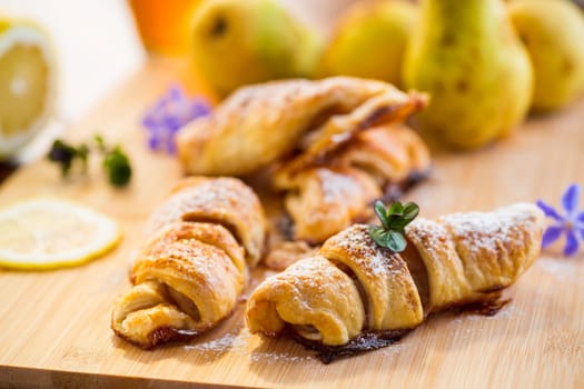 Sweet pastries, puff pastries with pears, on a wooden table .