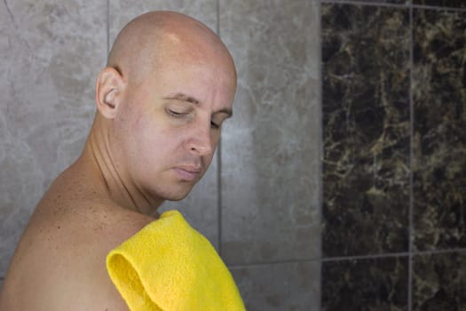 Man rubs his shoulder with washcloth in the shower, care and hygiene of body and skin at home