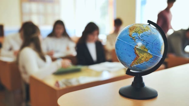 A globe of the world in a school classroom during a lesson. The globe shows North and South America.