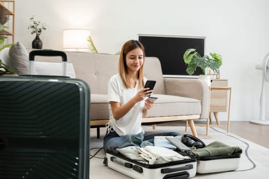 Young Asian tourist packs her suitcase, checks her belongings and passport in preparation for her weekend trip.