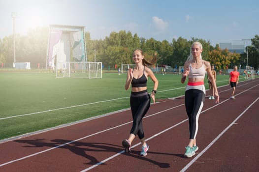 Two friends - athlete young woman runner train at the stadium outdoors