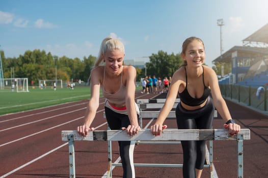 Two friends - athlete young woman runner train at the stadium outdoors