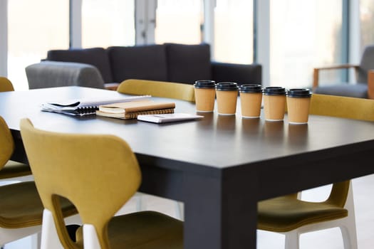 Empty office, meeting room and coffee on table with paperwork, seminar setup or advisory business workshop. Notebook, paper cup and furniture in boardroom at consulting agency for training conference.