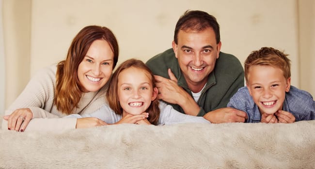 Happy family, parents and children in portrait on bed for love, peace and relax at home in bedroom. Connection, smile and people in house or apartment for mother, father and kids together in Spain.