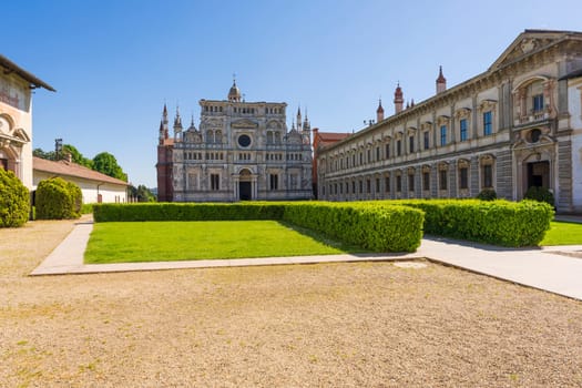 Certosa di Pavia monastery, historical monumental complex that includes a monastery and a sanctuary. green court and a church.The Ducale Palace on the right,Pavia,Italy.