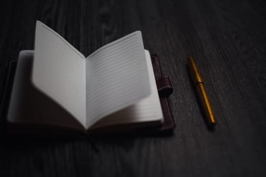 Subject shooting - Notepad and gold pen. Blank notepad on a darck wood. High quality photo