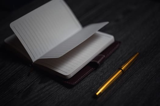 Subject shooting - Notepad and gold pen. Blank notepad on a darck wood. High quality photo