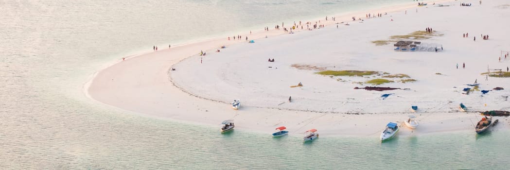 Zanzibar beach with a lot of people and a boat in the water. Scene is relaxed and fun, summer concept, Tanzania, Zanzibar