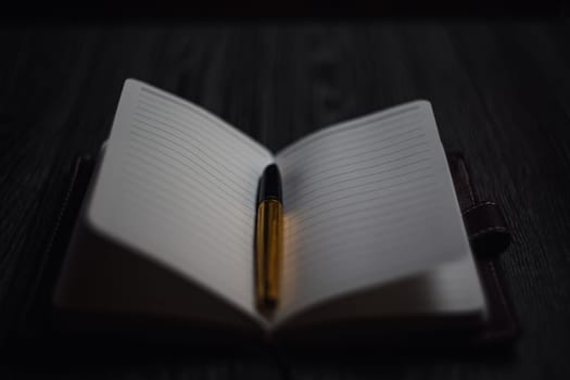 Subject shooting - Notepad and gold pen. Blank notepad on a darck wood. High quality photo