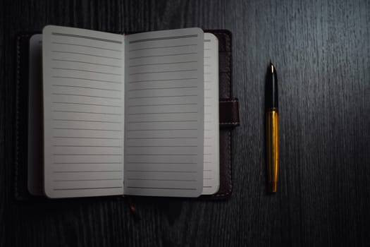 Subject shooting - Notepad and gold pen. Blank notepad on a darck wood. High quality photo