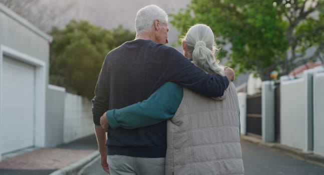 Senior couple, walk and hug outdoor in city, road and driveway of house for love, peace and support. Elderly people, freedom and retirement together in nature, environment or urban with back view.