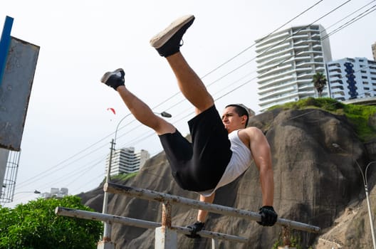 Handsome man exercising on parallel bars on the street outdoors