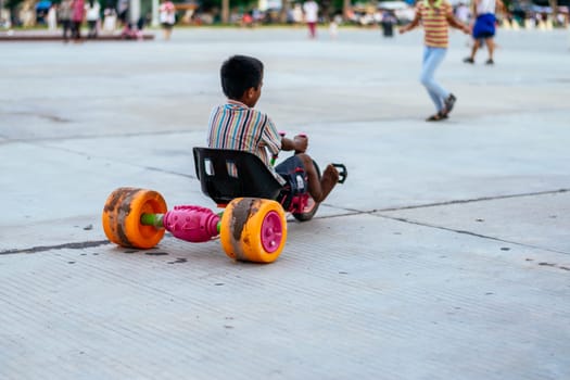 Unrecognizable boy with his back turned in the park driving a toy car before the pandemic