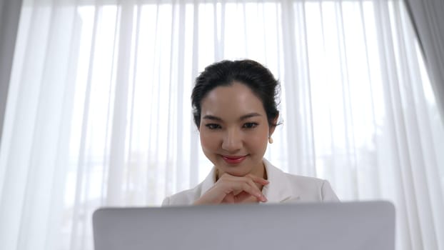 Young businesswoman sitting on the workspace desk using laptop computer for internet online content writing or secretary remote working from home. Vivancy