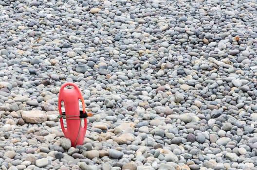 Red plastic buoyancy aid in the sand on lonely beach