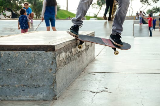 Skateboarder is doing a crooked grind trick on a bench in skatepark