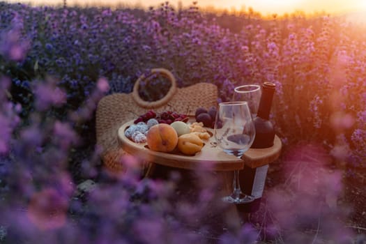 A picnic basket filled with fruit and wine is set out in a field of purple flowers. The scene is serene and peaceful