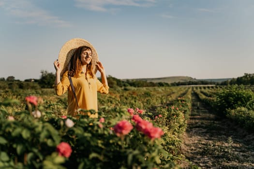 A woman wearing a straw hat stands in a field of pink flowers. She is smiling and she is enjoying the beautiful scenery