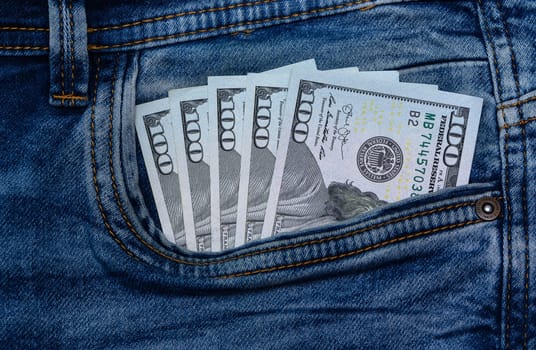 One hundred dollar banknote money in pocket jeans pants background texture. 100 dollar bill close up