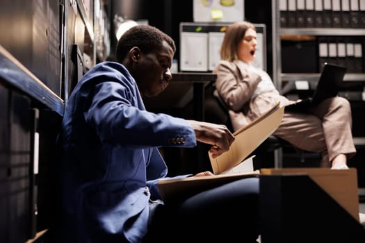 Inspectors working overhours in evidence room, checking crime scene files discussing criminology report. Tired private detectives analyzing victim report, trying to catch mysterious suspect