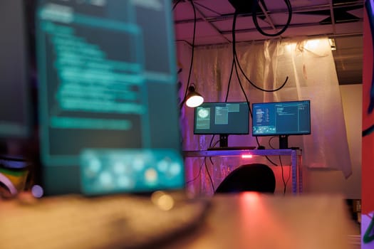 Computer screens with malware running code stealing sensitive information in hackers abandoned warehouse. Malicious software with internet virus on monitors in dark hideout with neon light