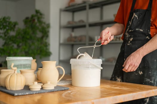 Close-up of a potter's hands glazing a ceramic mug