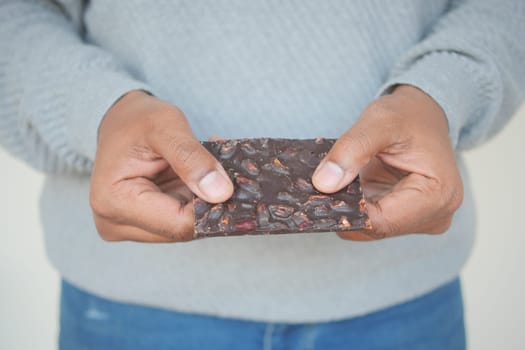 man hand holding a dark chocolate with mixed nut .