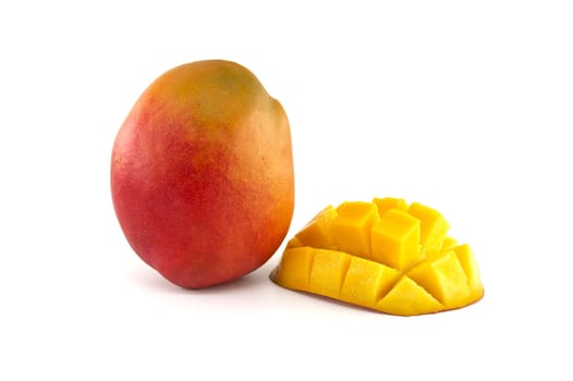 Ripe mango with red and yellow skin near cut half mango with the flesh cubed
