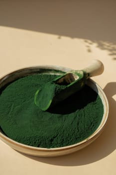 Organic blue-green algae spirulina powder food in plate with wooden spoon. Copy space for your text Health benefits of spirulina chlorella. Vitamins and minerals to diet. Detox dietary supplement Seaweed superfood concept