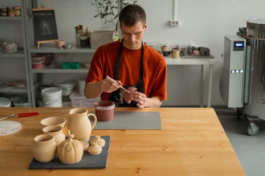 Potter paints ceramic dishes with a brush