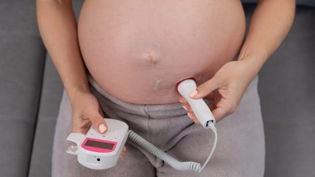 Close-up of a pregnant woman's belly using a home doppler. Blank screen