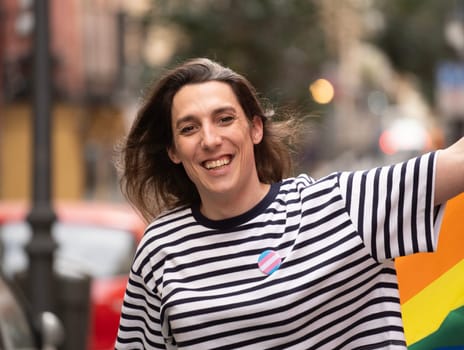 Headshot of a transgender woman smiling and walking in a urban street. Concept of pride and transgender community.