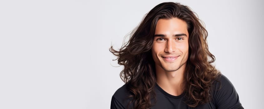 Portrait of an elegant sexy smiling Latino man with perfect skin and long hair, on a white background. Advertising of cosmetic products, spa treatments shampoos and hair care products, dentistry and medicine, perfumes and cosmetology for men