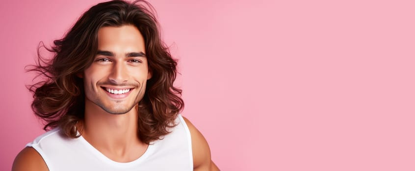 Portrait of an elegant sexy smiling Latino man with perfect skin and long hair, on a pink background. Advertising of cosmetic products, spa treatments shampoos and hair care products, dentistry and medicine, perfumes and cosmetology for men